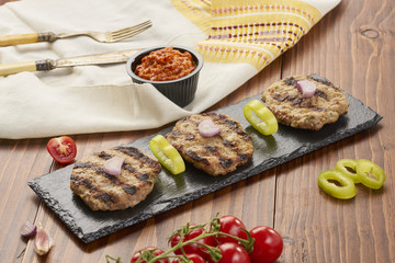 Grilled Veal minced meat with spices on black stone and wooden background 