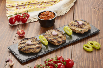 Fototapeta na wymiar Grilled Veal minced meat with spices on black stone and wooden background 
