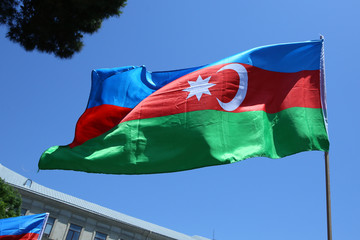 The Azerbaijani flag is on the background of the city . Action . Azerbaijan flag in Baku, Azerbaijan. National sign background. Red Green Blue flag. Azerbaijan tradition patriotic. Flags waving wind