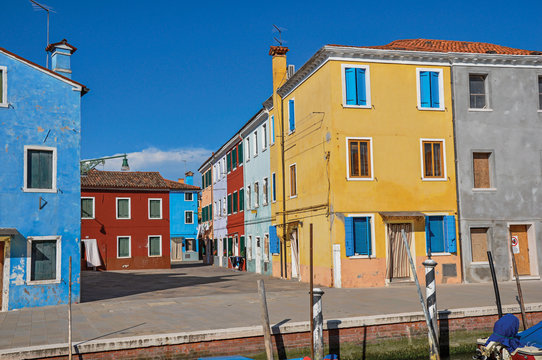 Overview of colorful buildings and clothes hanging in a blue sunny day, in front of a canal at Burano, a gracious little town full of canals, near Venice. Located in the Veneto region, northern Italy © Celli07