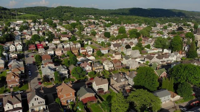 A slow forward aerial establishing shot view of a residential neighborhood in a small Pennsylvanian town in the early evening. Pittsburgh suburbs.  	