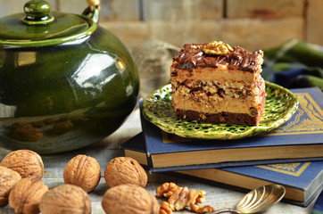 Nut cake with cream and chocolate icing on a rustic background