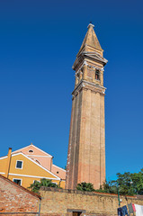 Overview of colorful buildings and leaning bell tower in a blue sunny day at Burano, a gracious little town full of canals, near Venice. Located in the Veneto region, northern Italy