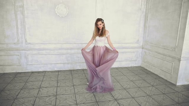 Beautiful young adult girl turns in purple dress in slow motion.