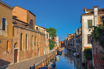 Panoramic view of buildings, bridge and boats in front of a canal at the sunset, in the city center of Venice, the historic and amazing marine city. Located in the Veneto region, northern Italy