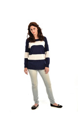 full length portrait of girl wearing striped blue and white jumper and jeans. standing pose on white studio background