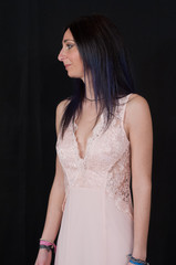 Portrait of a beautiful young brunette girl in an evening dress with pink lace and pink fartine on a black background