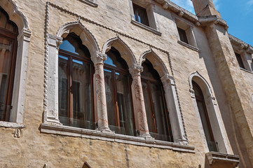 Fototapeta premium Close-up of windows with columns and arches in typical Venetian style in ancient building. At the city center of Venice, the historic and amazing marine city. Located in Veneto region, northern Italy
