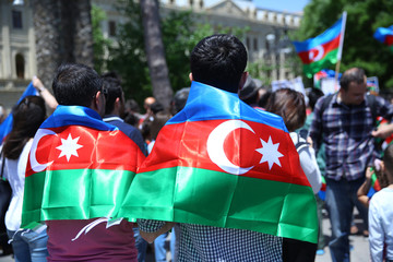 The Azerbaijani flag is on the background of the city . Action . Azerbaijan flag in Baku, Azerbaijan. National sign background. The boy put a flag on his shoulder.