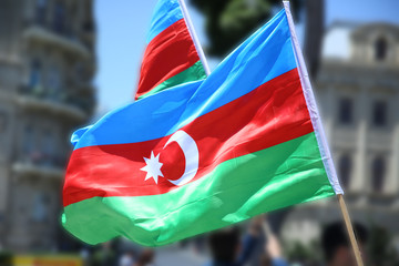 The Azerbaijani flag is on the background of the city . Action . Azerbaijan flag in Baku, Azerbaijan. National sign background. Red Green Blue flag. Azerbaijan tradition patriotic. Flags waving wind