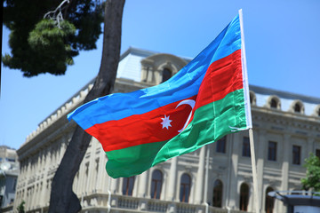 The Azerbaijani flag is on the background of the city . Action . Azerbaijan flag in Baku, Azerbaijan. National sign background. Red Green Blue flag. Azerbaijan tradition patriotic. Flags waving wind