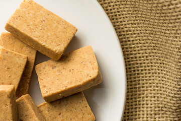 Pacoca is a candy with peanuts from Brazil. Sweet food of Festa Junina, a typical brazilian party. Snacks on bowl and jute, burlap fabric.