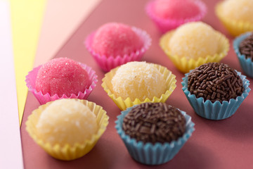 Brigadeiro, Beijinho and Bicho de Pe: sweets from Brazil. Child birthday party. Candy balls in a straight line. Colorful background.