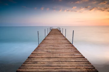 Foto op Canvas sunset pier wit clouds in the sea of minimalism © artemgukasov