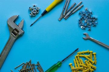 A set of tools and nails on a blue background. Text, screwdriver, wrench, nails, nozzles, nuts. Place under the text