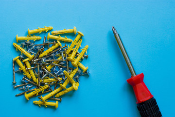 A bunch of different nails and a red screwdriver on a blue background