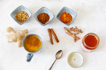Turmeric latte ingredients. Ground turmeric, curcuma root, cinnamon, ginger, grey ceramic bowls on grey cincrete background. Top view, copy space