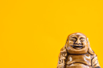 Ceramic Statue of Laughing Buddha on Bright Orange Background. Buddhism Religious Symbol. Minimalist Inspirational Image with Copy Space for Quotes.