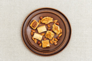 Turkish sweet with chopped nuts and honey. Delicious Middle Eastern honey dessert on clay plate. Top view.