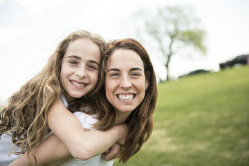 Obraz premium Mother Giving Daughter Ride On Back In Park