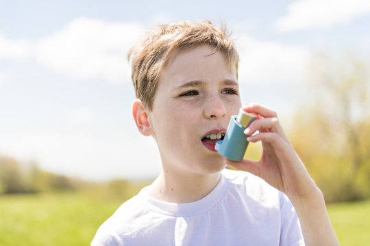 child using inhaler for asthma outside in a park