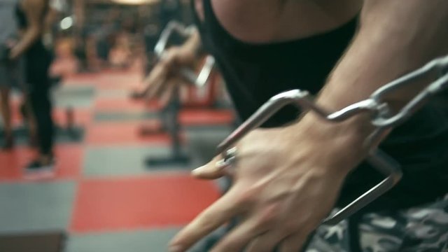 Bodybuilder doing cable crossover fly, shallow depth of field. Focus on hand, slow motion
