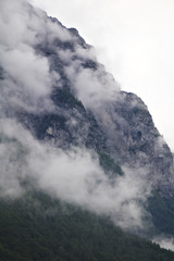 foggy clouds rising from dark alpine mountain forest