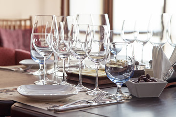 Elegant dishware and wine glasses on the table in the interior