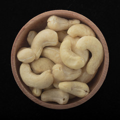 cashew in wooden cup isolated on black background. top view