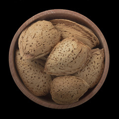 almonds in wooden cup isolated on black background. top view