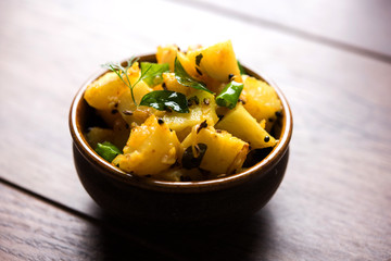 Chatpate Masala Aloo Sabzi fry OR Bombay potatoes served in a bowl, selective focus