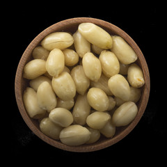 shelled groundnut in wooden cup isolated on black background. top view