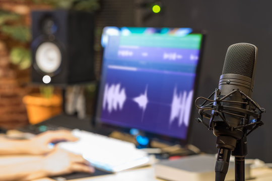 condenser microphone on sound engineer hands editing voice waveform background in broadcasting studio