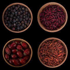 set of dried berries in wooden cups  isolated on black. top view