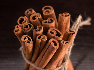 cinnamon tied with jute rope on a dark wooden background, soft focus, in a low key
