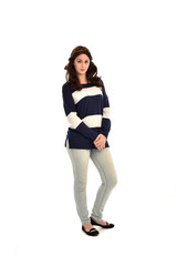  full length portrait of girl wearing striped blue and white jumper and jeans. standing pose on white studio background