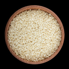 seeds of white sesame in wooden cup isolated on black. top view
