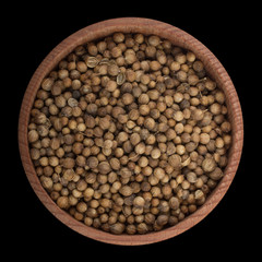 coriander in wooden cup isolated on black. top view