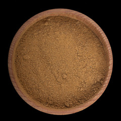 iground cinnamon n wooden cup isolated on black. top view