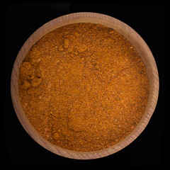 ground red cayene pepper in wooden cup isolated on black. top view