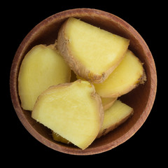 islices of ginger in wooden cup isolated on black. top view