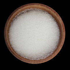 white sugar in wooden cup isolated on black. top view