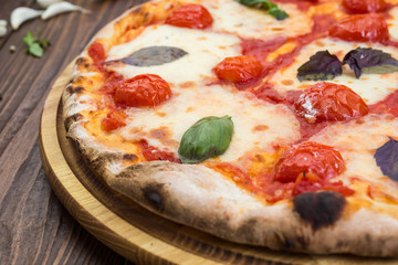 rustic italian pizza Margarita with mozzarella, cherry tomatoes and basil leaves on wooden background