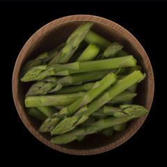 Asparagus in wooden cup isolated on black. top view