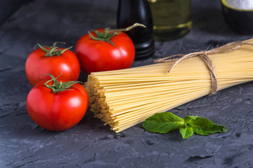 Uncooked pasta spaghetti with ingredients for tomato sauce. Concept of the composition of food design.