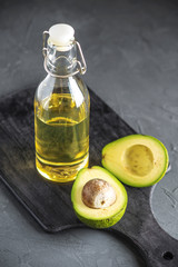 Avocado fruit and oil in glass bottle on dark background. Concept organic eco products for food and cosmetic procedures
