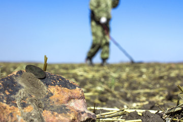 the old lost coin in the field, on the blurred background of the treasure hunter with a metal detector