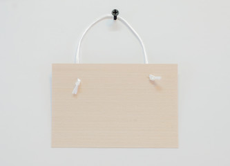 The sign is made of wood, natural color and texture, with a rope