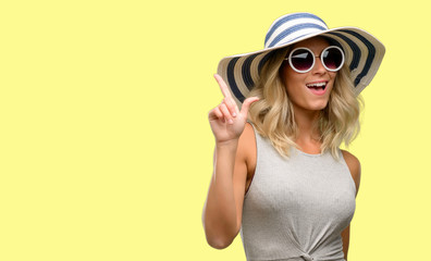 Fototapeta premium Young woman wearing sunglasses and summer hat pointing away side with finger