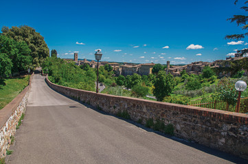 Fototapeta premium View of Colle di Val d Elsa town with bridge and vegetation at the front. A graceful village with its historic center preserved and known by its crystal production. Located in the Tuscany region 